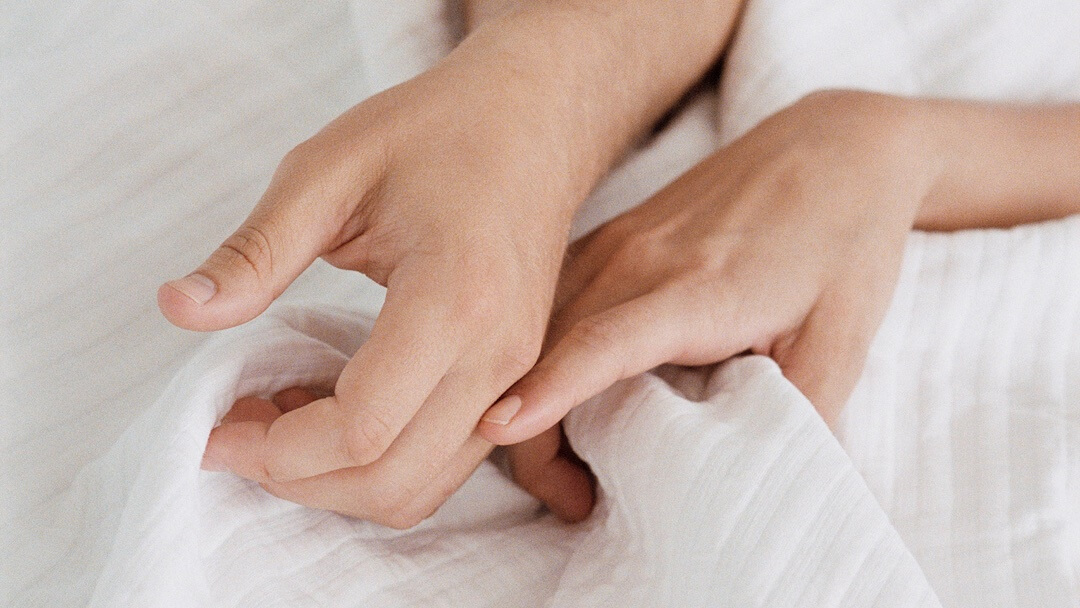 couple-in-bed-holding-hands