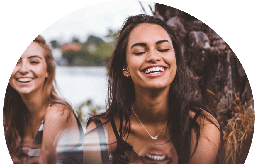 two-women-laughing-sitting-at-the-base-of-a-tree