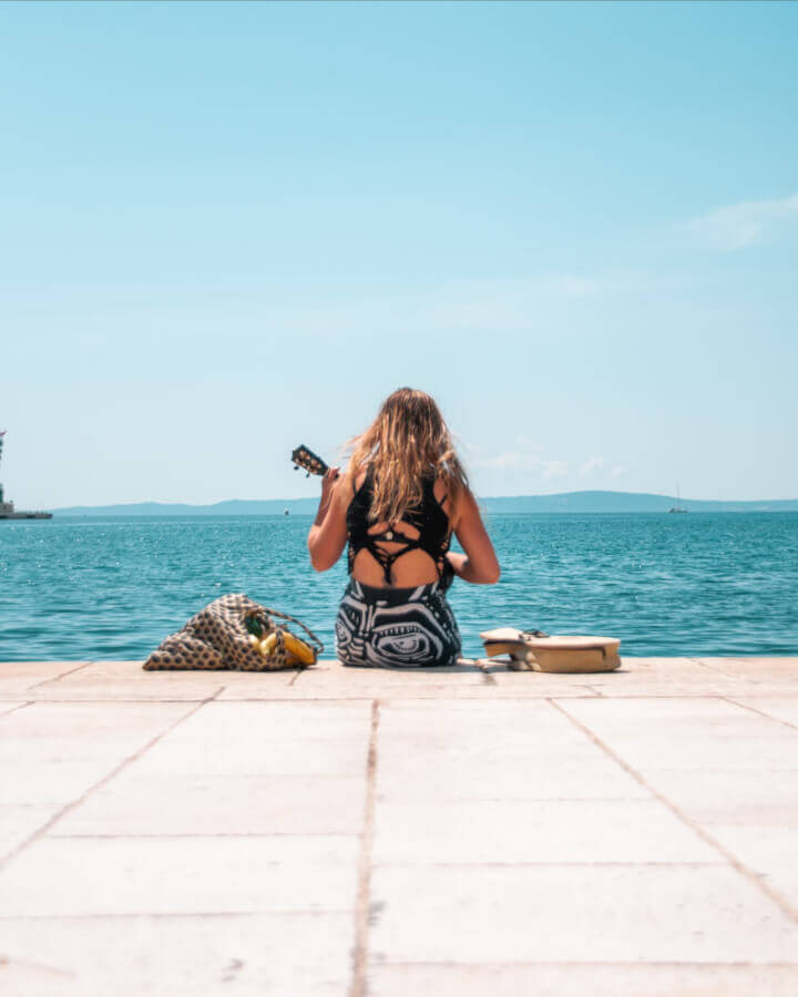 woman-playing-ukulele-sitting-by-the-sea